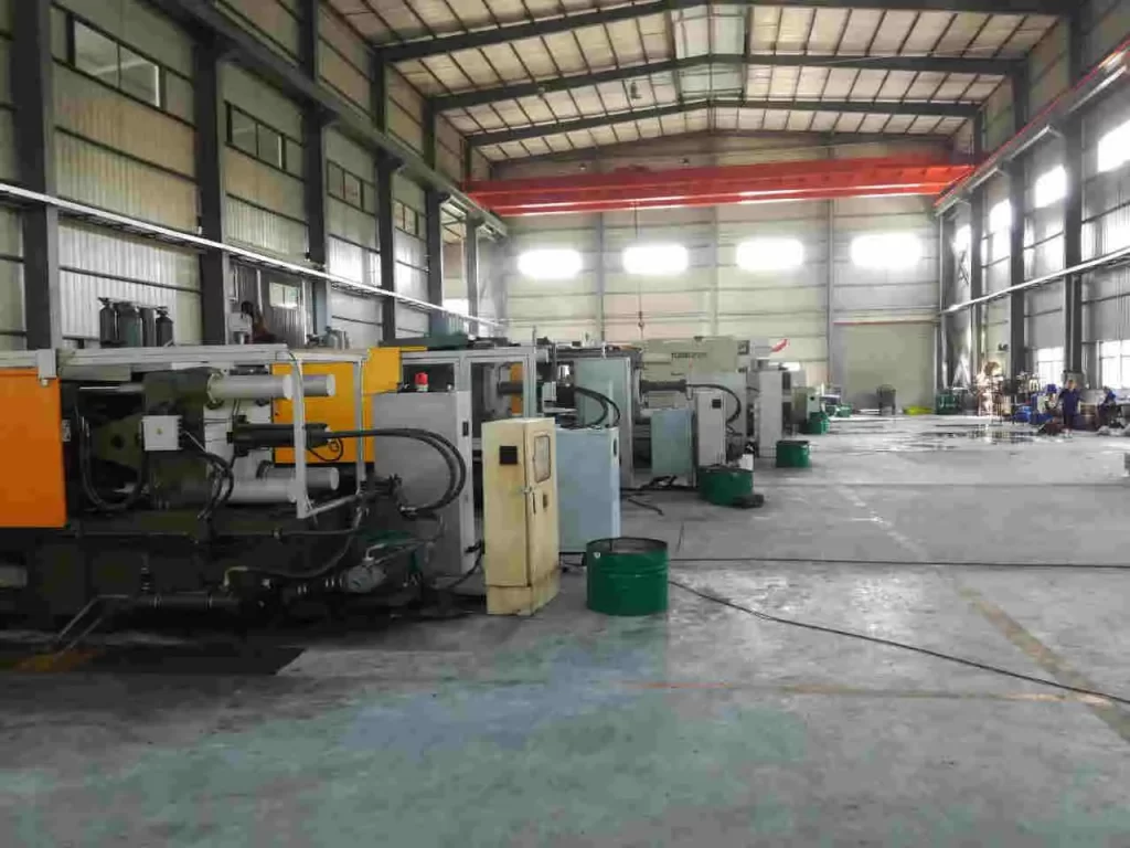 gdszsyx.com – Bright and spacious die casting workshop with multiple die casting machines aligned in a row, clean floor, high ceilings, and a worker operating equipment in the background.